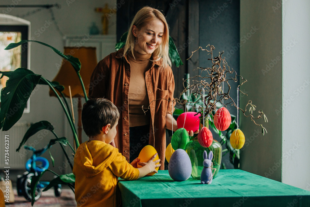Smiling mother and son decorating table for Easter dinner at home Smiling mother and son decorating table for Easter dinner at home
