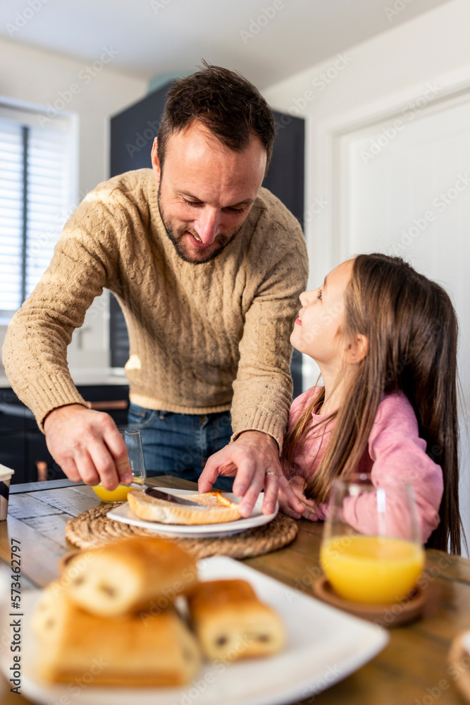 Smiling father serving breakfast to daughter at table Smiling father serving breakfast to daughter at table