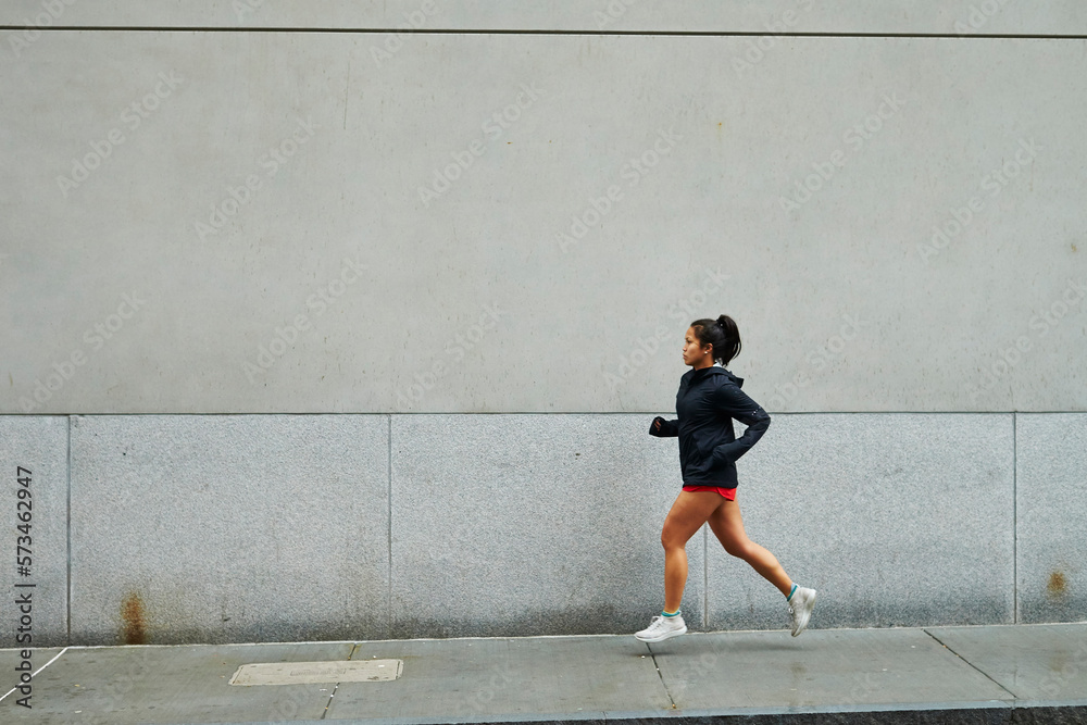 A young asian woman runs on a city street. A young asian woman runs on a city street.
