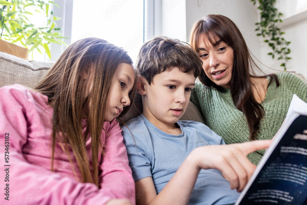 Boy reading book with sister and mother at home Boy reading book with sister and mother at home