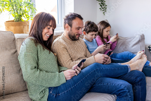 Happy man and woman with children using smart phone at home photo