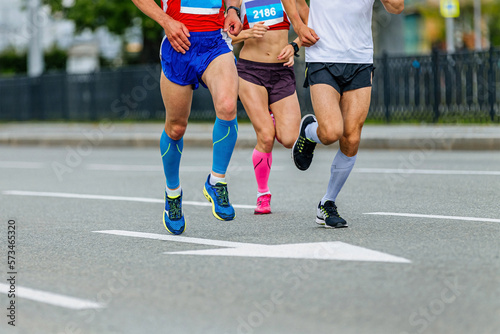 two male and female athletes in compression socks run city marathon