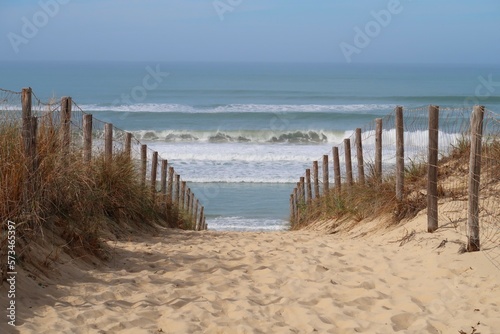 Fotografia Chemin de sable cloturé par une ganivelle et descendant vers la mer et la plage