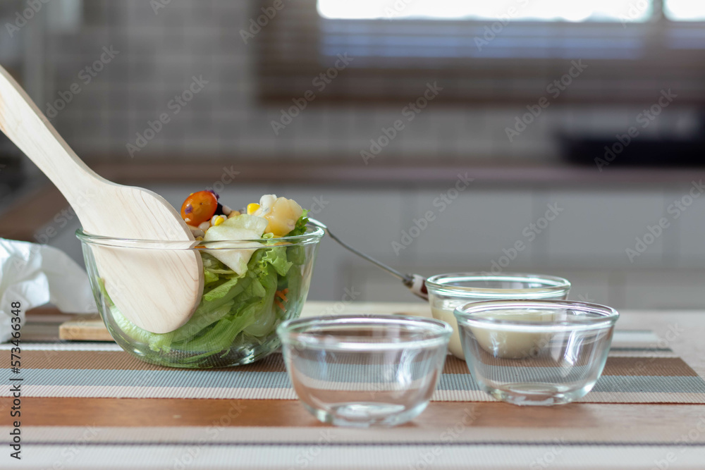 young woman is making salad from vegetables she has prepared on table in her home kitchen to get salad that is clean and safe because ingredients are carefully selected. healthy food preparation ideas young woman is making salad from vegetables she has prepared on table in her home kitchen to get salad that is clean and safe because ingredients are carefully selected. healthy food preparation ideas