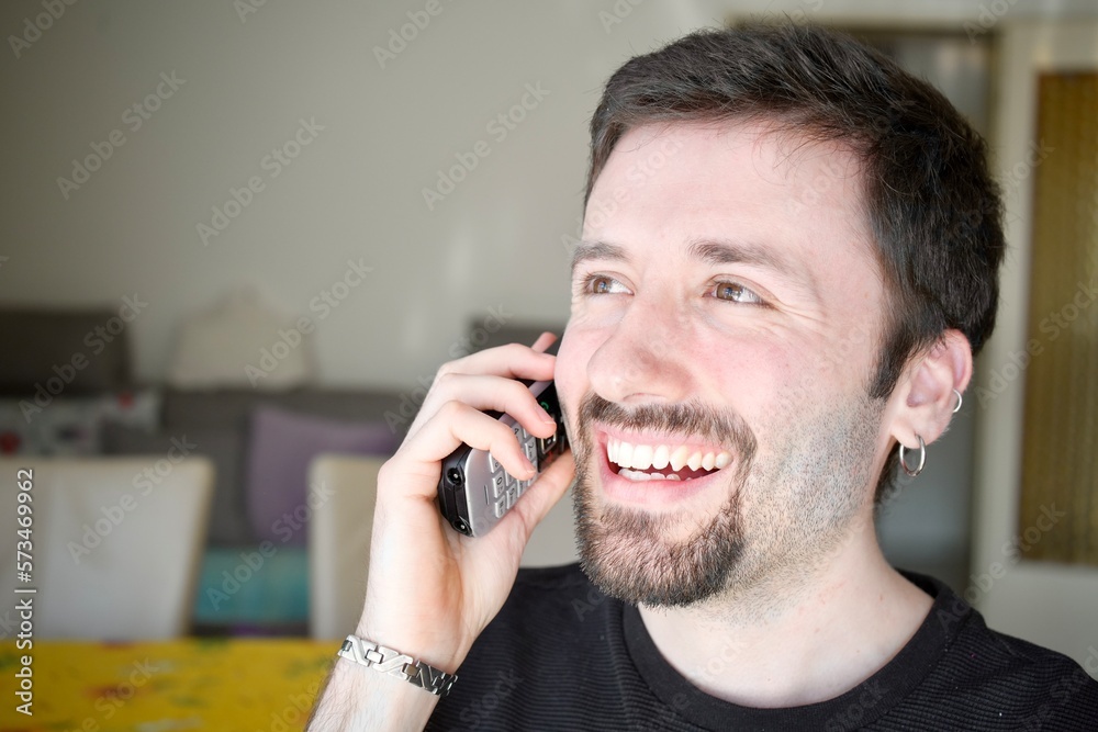 Happy man using a cordless phone to communicate with someone. The man's relaxed and cheerful expression conveys a positive message, during a social or business conversation. Happy man using a cordless phone to communicate with someone. The man's relaxed and cheerful expression conveys a positive message, during a social or business conversation.