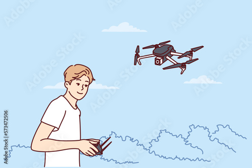 Teenage boy launches quadcopter using remote control and makes aerial photography from drone. Guy has hobby launching miniature aircraft or quadcopter with remote operation wanting to become operator 