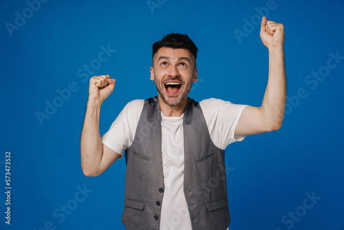 Satisfied man screaming and celebrating success isolated over blue wall