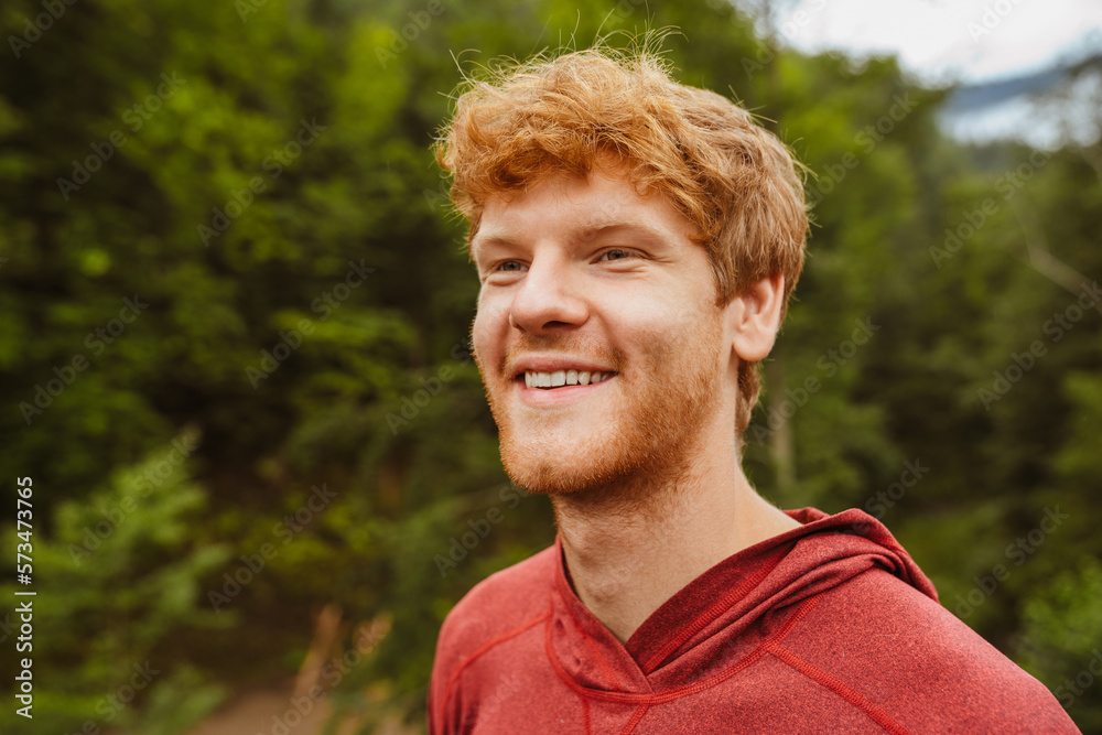 Cheerful redhead man smiling while standing outdoors Cheerful redhead man smiling while standing outdoors