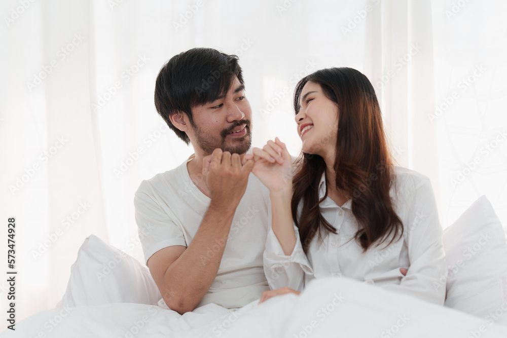 Beautiful asian couple in love and smiling sitting on bed. Romantic moment, relationships, family concept. Beautiful asian couple in love and smiling sitting on bed. Romantic moment, relationships, family concept.