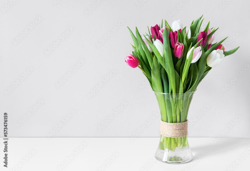 Colorful spring tulips in a vase on a white table.