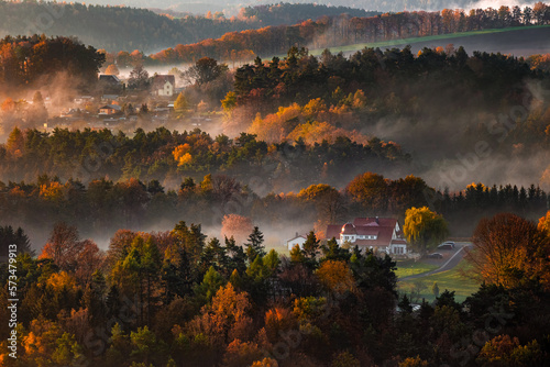 Saxon  Germany - Warm foggy autumn sunrise above the valley in Saxon Switzerland National park with fresh vivid autumn foliage and fog on the fields
