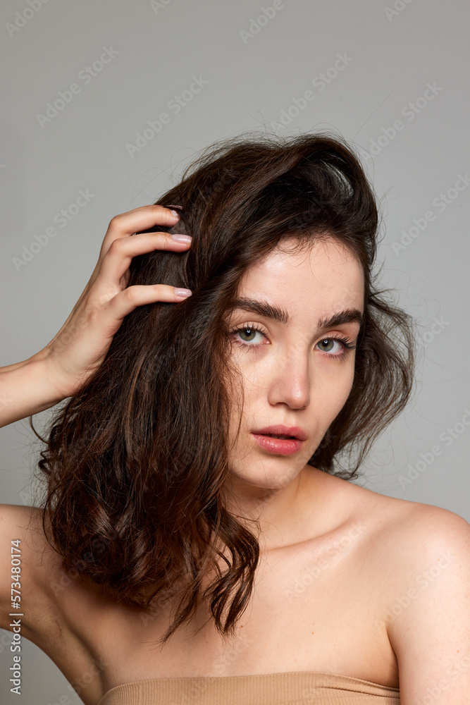 Curly heatlhy hair. Portrait of young beautiful brunette girl with well-kept skin over grey studio background. Concept of natural beauty, skincare, cosmetology, plastic surgery, health Curly heatlhy hair. Portrait of young beautiful brunette girl with well-kept skin over grey studio background. Concept of natural beauty, skincare, cosmetology, plastic surgery, health
