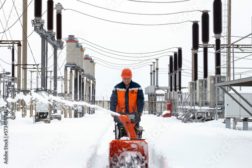 A man removes snow with a snowplow.