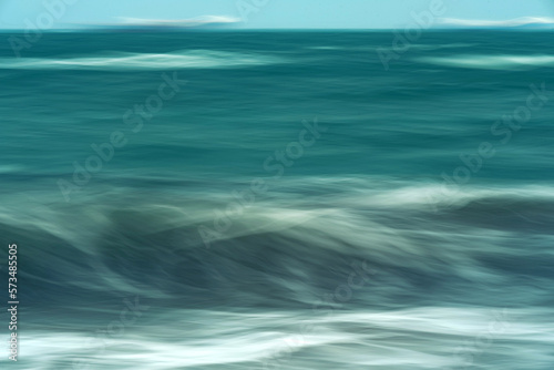 Abstract intentional camera movement of textured blurred aqua green waves of the natural flow of the ocean