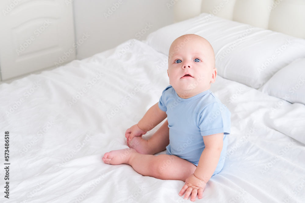 portrait of smiling baby boy with big blue eyes in bodysuit on white bedding. Healthy newborn child portrait of smiling baby boy with big blue eyes in bodysuit on white bedding. Healthy newborn child