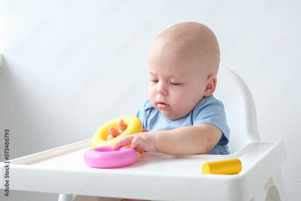 cute baby boy playing with colorful plastic toys at child chair. early children development cute baby boy playing with colorful plastic toys at child chair. early children development