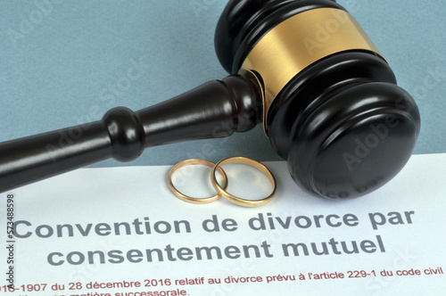 Concept de divorce par consentement mutuel avec des alliances et un marteau de juge sur fond bleu photo