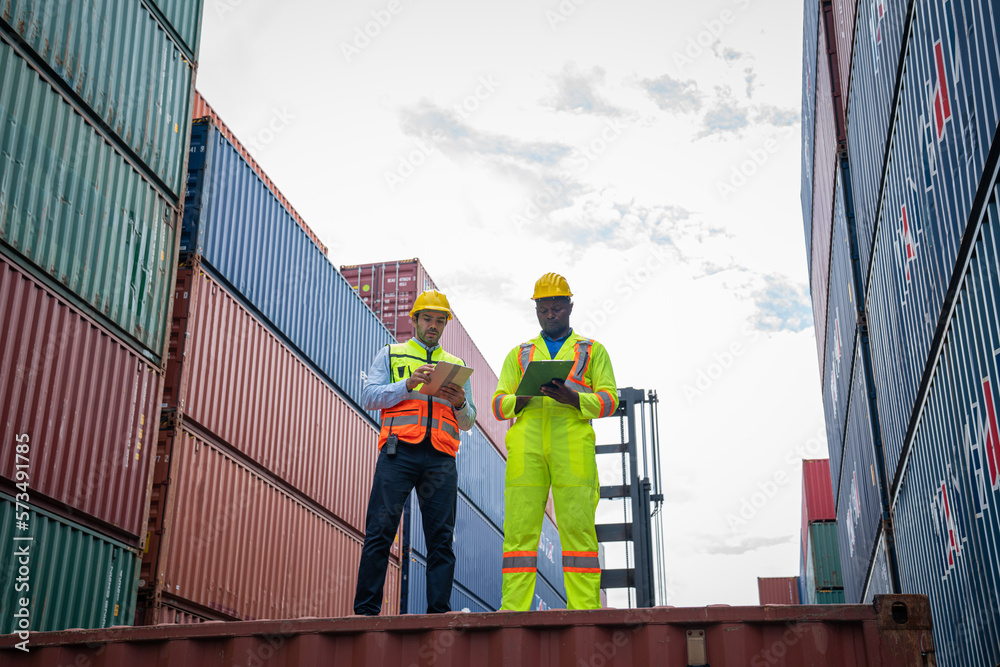 Male Industrial Engineer and Foreman control checking container at container yard warehouse. Logistics business. Import and export concept. Male Industrial Engineer and Foreman control checking container at container yard warehouse. Logistics business. Import and export concept.
