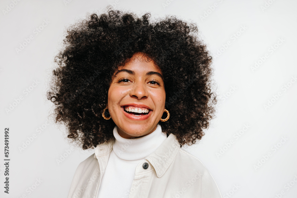 Young woman with curly hair smiling at the camera in a studio Young woman with curly hair smiling at the camera in a studio