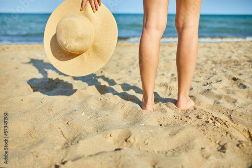 Woman hold in hand straw hat on yhe beach near sea, Summer vacation and travel. Copy space