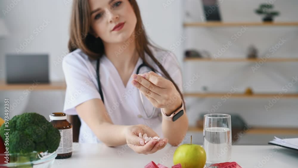 Holding pills in hands. Female doctor nutritionist in white uniform is in the clinic. Holding pills in hands. Female doctor nutritionist in white uniform is in the clinic.