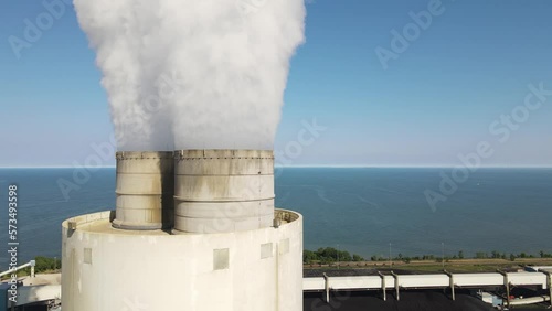 Power plant emit smoke into atmosphere with endless sea in background, aerial view photo