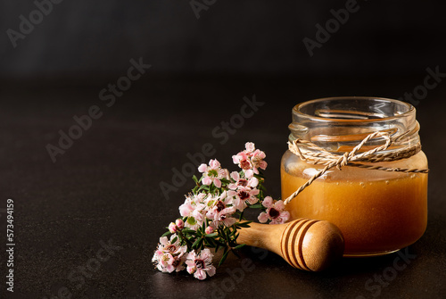 Manuka flowers and honey on ceramic black background. photo
