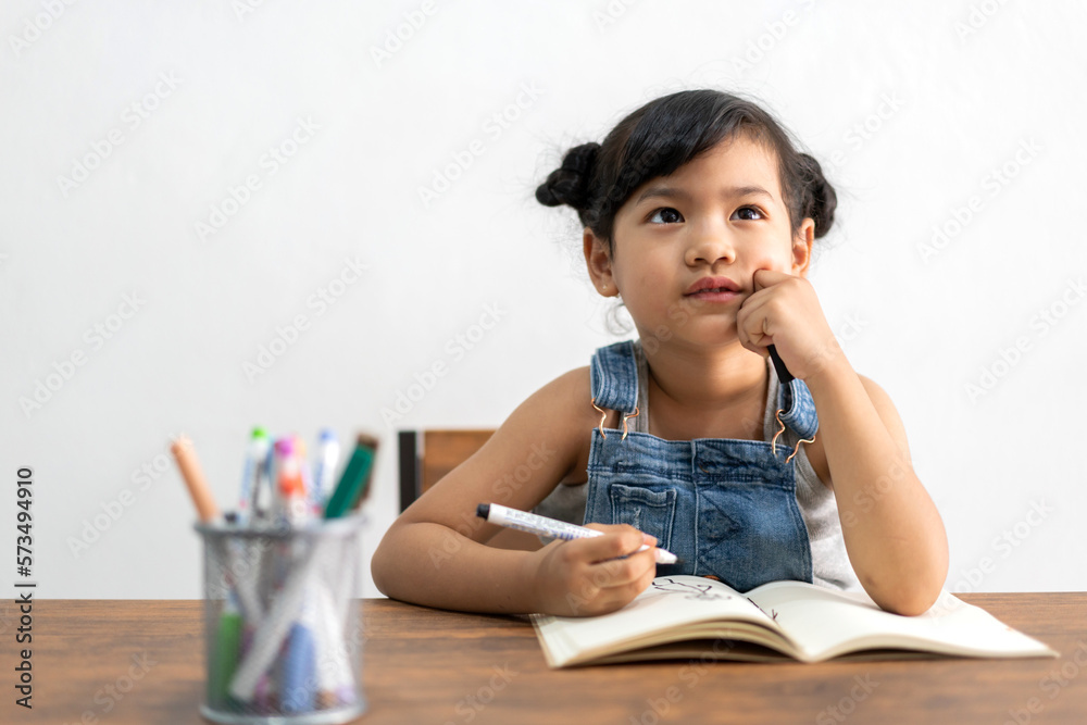 Portrait enjoy happy little asian girl learn and study on table.Asian young girl writing and paint with paper book make homework in homeschool at home.Education Portrait enjoy happy little asian girl learn and study on table.Asian young girl writing and paint with paper book make homework in homeschool at home.Education