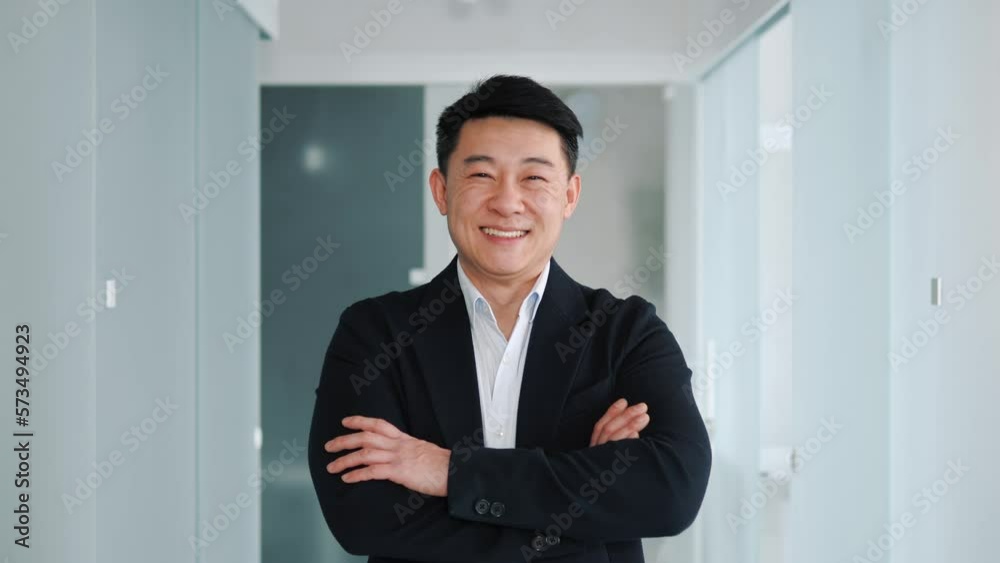 Japanese face portrait. Handsome smiling asian business man in formal suit looks at camera in office hallway. East Asian male businessman working on financial, marketing, banking projects. Japanese face portrait. Handsome smiling asian business man in formal suit looks at camera in office hallway. East Asian male businessman working on financial, marketing, banking projects.