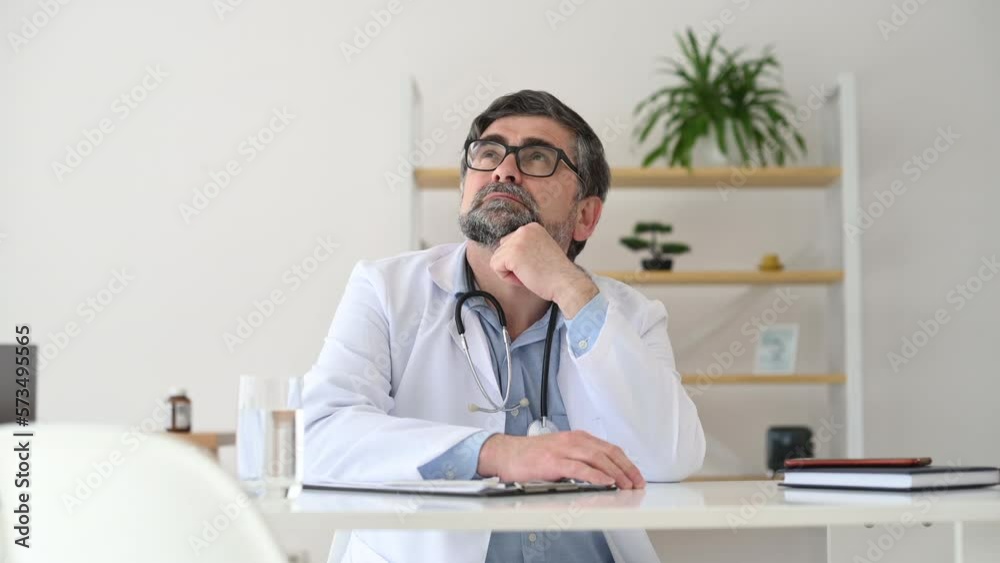 Mature male doctor in coat is in the clinic room.