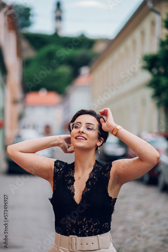 Woman fixing her hair with hands while walking in the city street