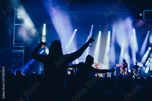 Silhouette of a woman with raised hands on a concert