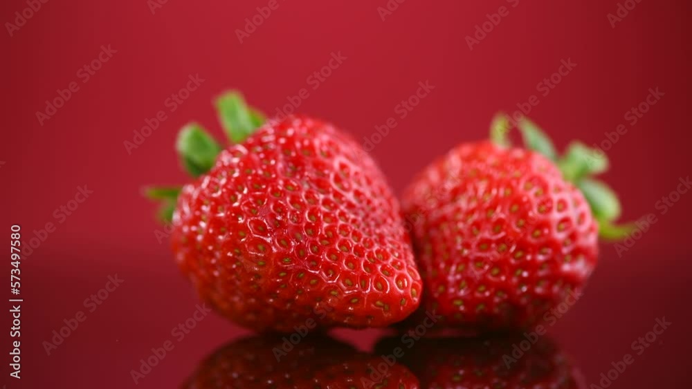Strawberries on a red background. Two Fresh ripe strawberries rotating on red, macro shot of fresh juicy berries, close up Strawberries on a red background. Two Fresh ripe strawberries rotating on red, macro shot of fresh juicy berries, close up