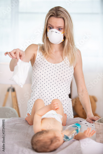 mother with gas mask changing smelly diaper