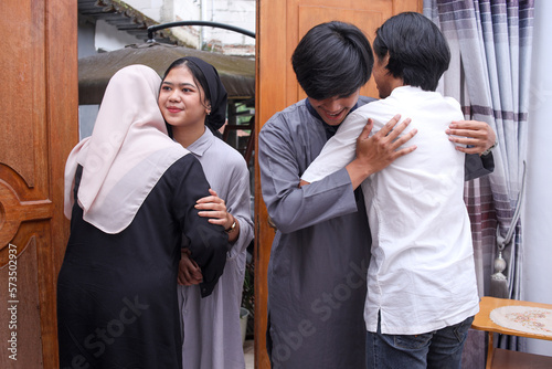 Young muslim people hand shaking, hugging, asking for apologize during eid mubarak moment.