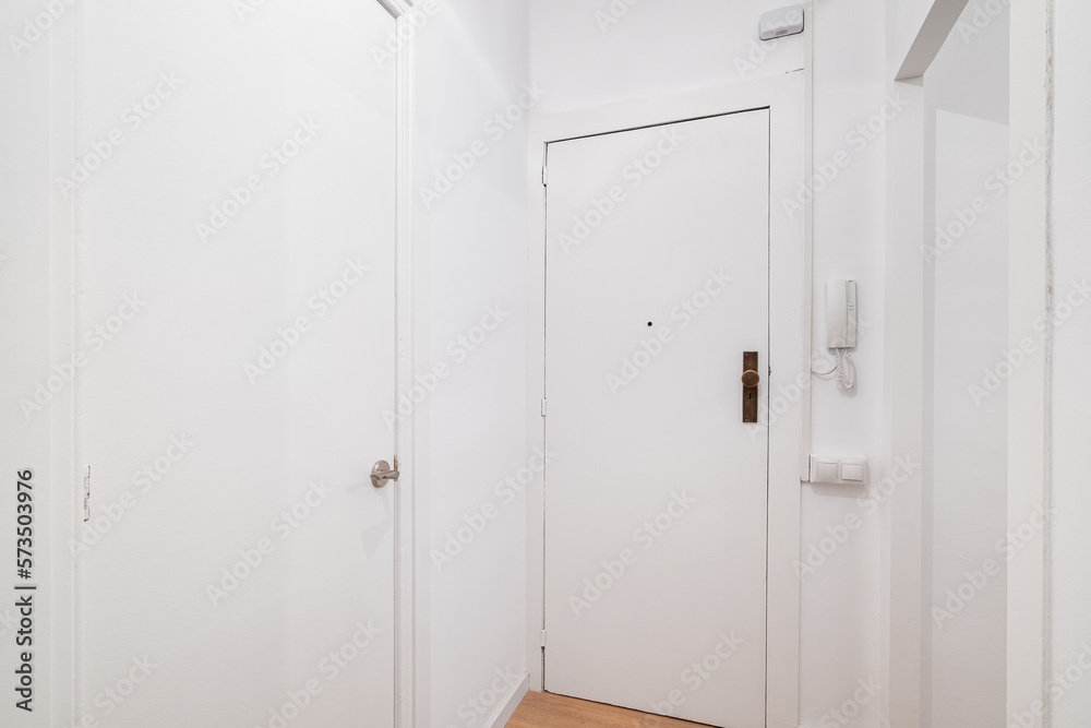 White front door to apartment with intercom on wall. There is peephole in door for observing what is happening outside. Door lock protects the apartment from the entry of unauthorized persons White front door to apartment with intercom on wall. There is peephole in door for observing what is happening outside. Door lock protects the apartment from the entry of unauthorized persons