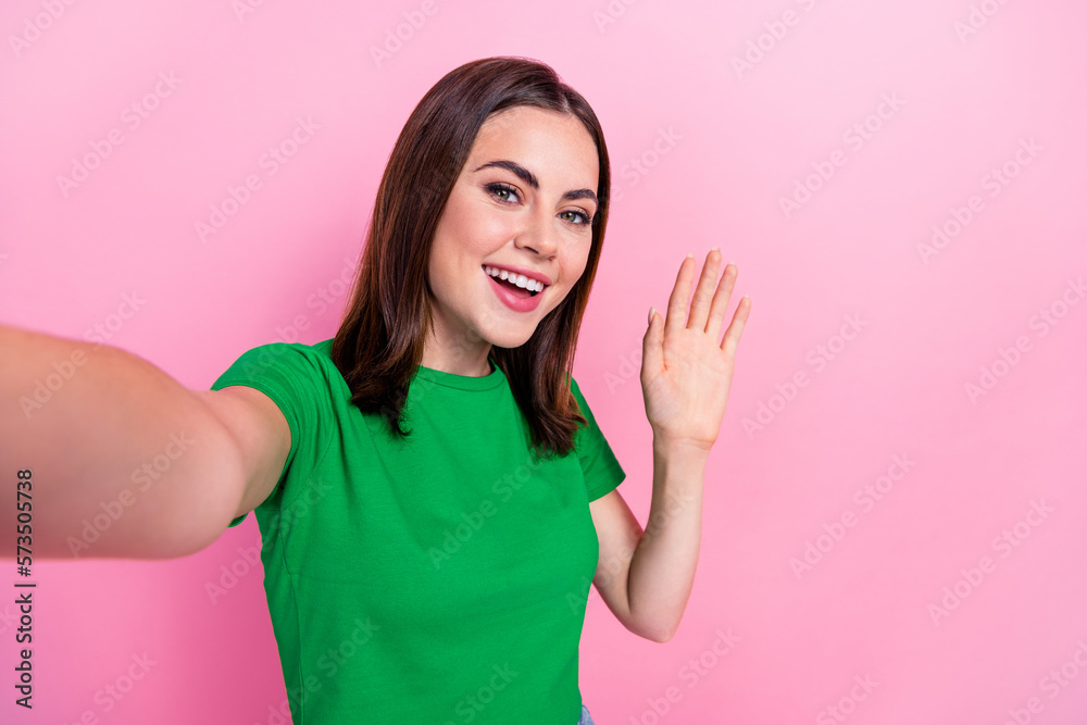 Photo of adorable excited lady dressed green t-shirt smiling waving arm palm recording video vlog isolated pink color background Photo of adorable excited lady dressed green t-shirt smiling waving arm palm recording video vlog isolated pink color background