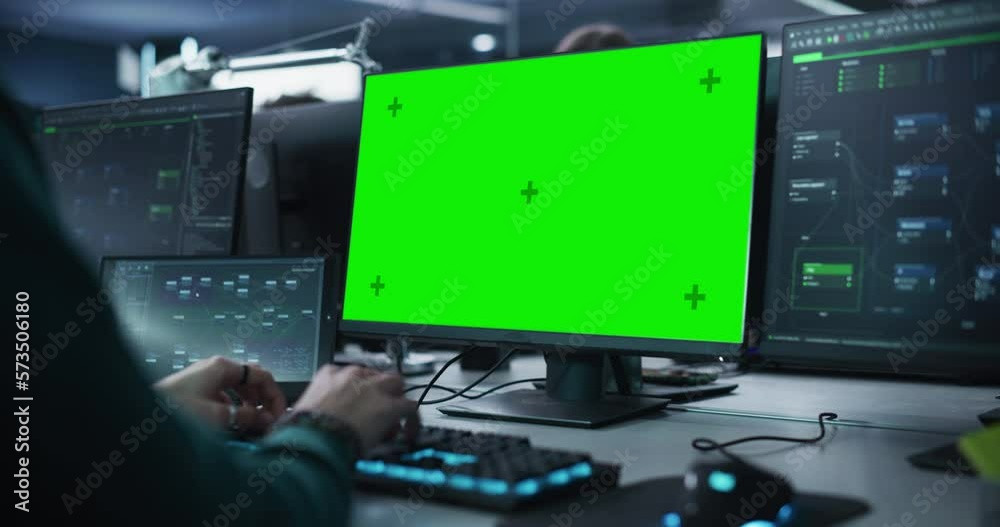 Close Up of a Software Developer Working on a Desktop Computer with Green Screen Mock Up Display. Specialist Typing on Keyboard, Coding and Implementing a New Technical Feature. Static Footage
