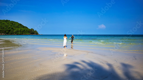 Phu Quoc island, Vietnam - March 31, 2019: White sand beach, sea horizon. Calm sea and girls walking on the beach. Coast of the South China Sea