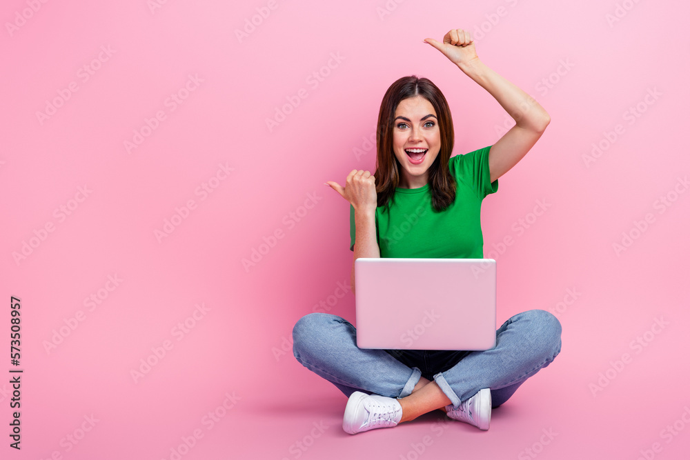 Full length photo of shiny excited lady dressed green t-shirt working modern gadget thumbs empty space isolated pink color background Full length photo of shiny excited lady dressed green t-shirt working modern gadget thumbs empty space isolated pink color background