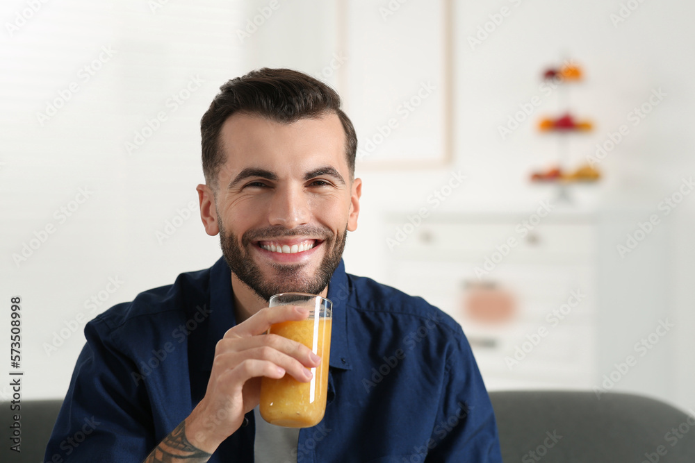 Fototapeta premium Handsome man with delicious smoothie at home. Space for text