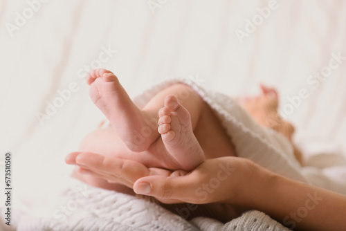 Mother and her newborn baby on white knitted plaid, closeup