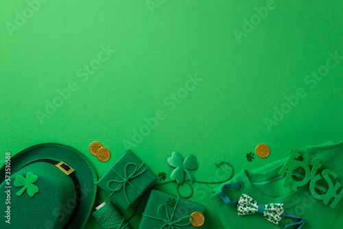 St Patrick's Day concept. Top view photo of green pullover leprechaun hat irish party glasses spool of twine present boxes gold coins shamrocks and confetti on isolated green background with copyspace