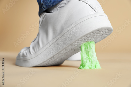 Fotografie Person stepping into chewing gum on light brown background, closeup