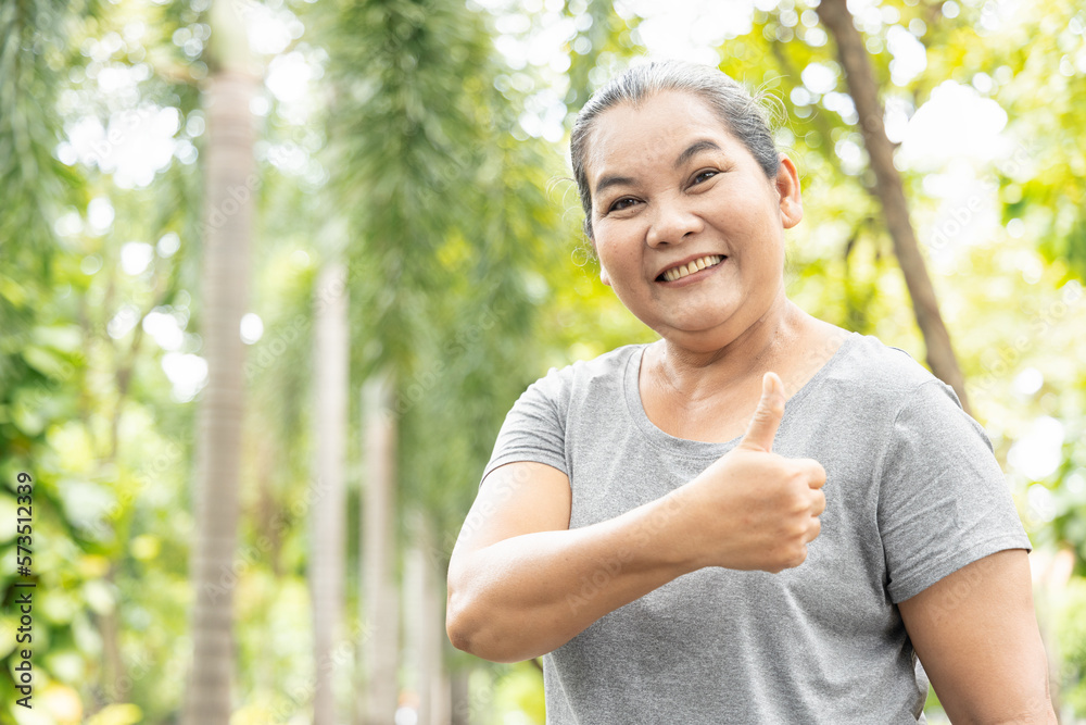 Exciting successful old asian senior woman giving thumb up gesture with happy and positive feeling in outdoor green park Exciting successful old asian senior woman giving thumb up gesture with happy and positive feeling in outdoor green park