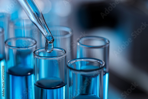 Dripping liquid from pipette into test tube in laboratory, closeup