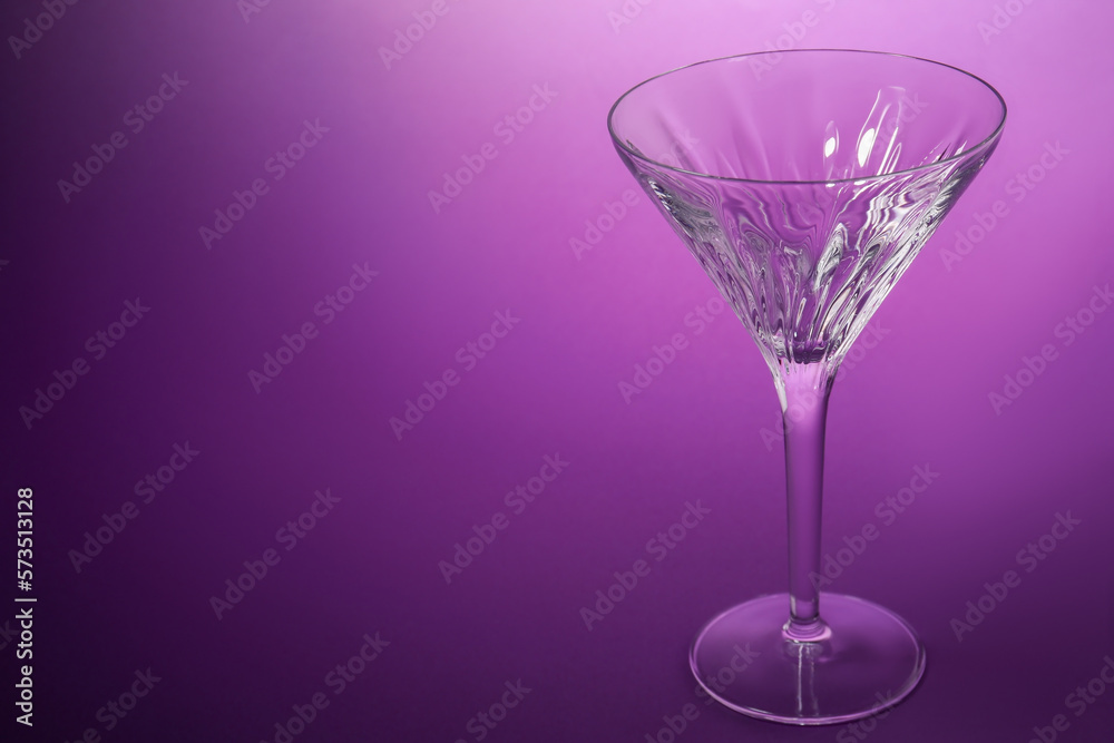 Elegant empty martini glass on purple background. Space for text Elegant empty martini glass on purple background. Space for text