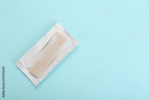 Fototapeta Naklejka Na Ścianę i Meble -  Unwrapped stick of chewing gum on light blue background, top view. Space for text
