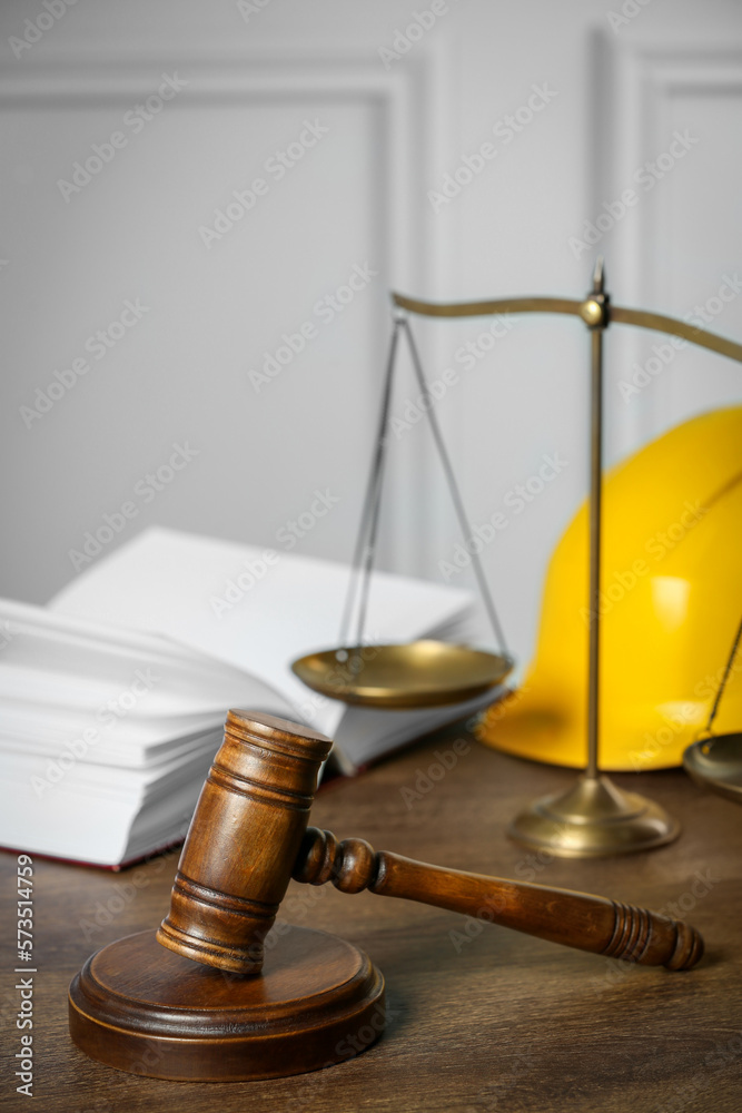 Labour, construction and land law concepts. Judge gavel, scales of justice, open book with hardhat on wooden table Labour, construction and land law concepts. Judge gavel, scales of justice, open book with hardhat on wooden table