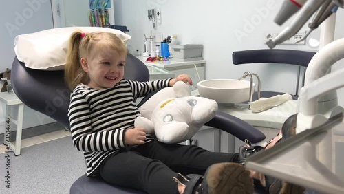 a little girl in a striped blouse in a dental office with a soft toy A sleepwalker or white astronaut laughs hugging waiting for a doctor no fear pediatric dentistry dentistry for children photo